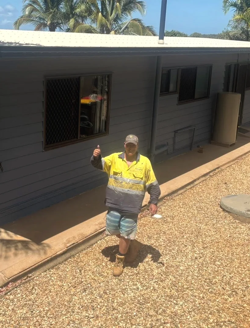 Graham Butler in hi-vis, thumbs up, in front of a freshly repainted house